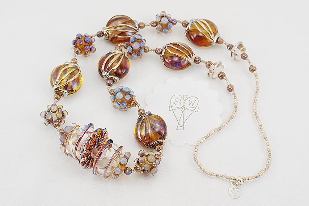 necklace made of opalescent bronze color glass beads accented with silver gold and lavender