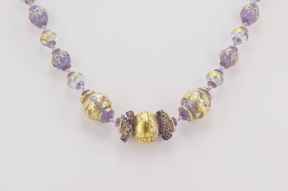 Handmade necklace with lavender colored glass beads accented with 22 karat gold and sterling silver.