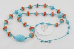 Turquoise necklace with reddish orange and yellow glass beads.