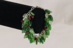 One of a kind bracelet with red and green glass holly leaves and berries .